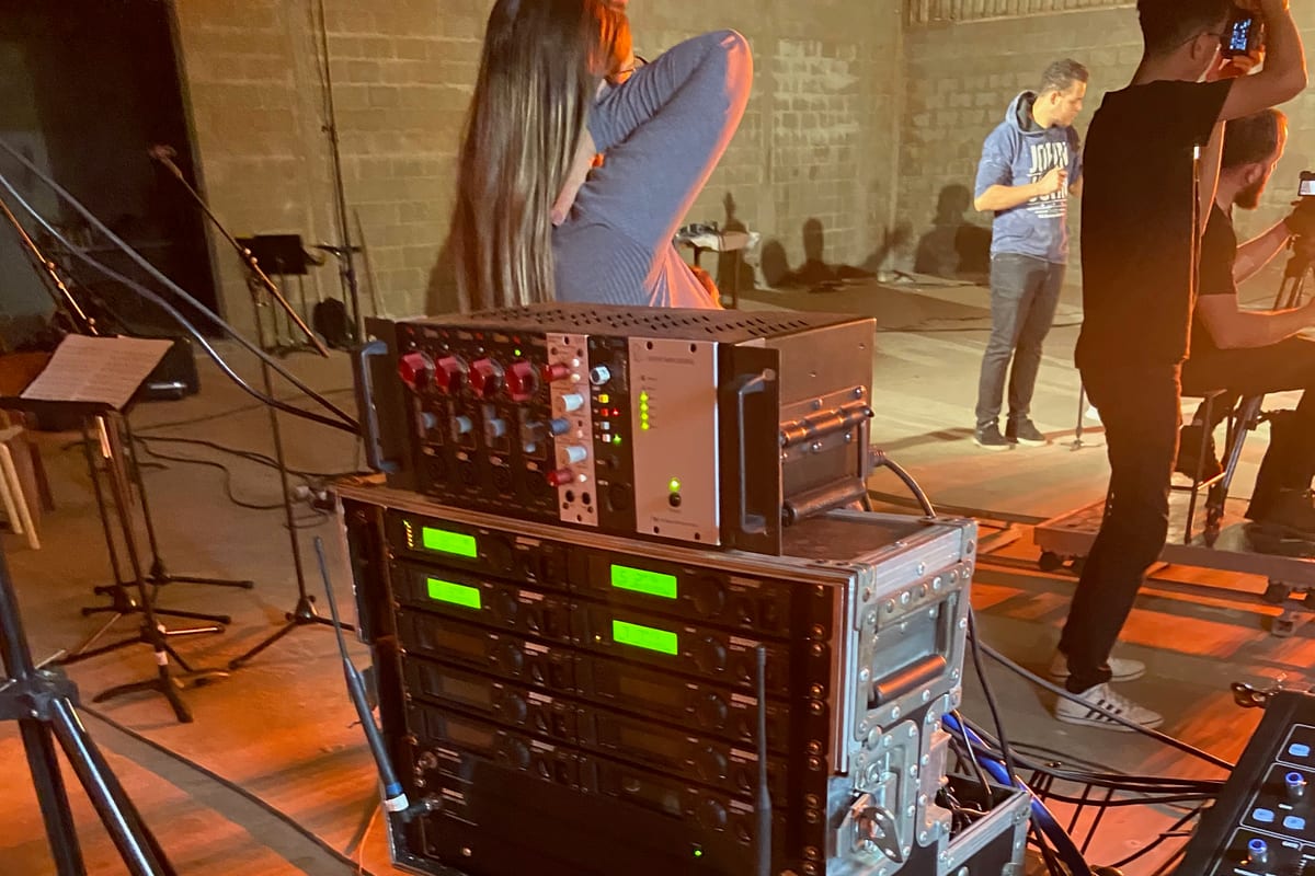 Backstage rack — power amplifiers stacked above a row of Shure ULX-D wireless receivers, antenna distribution and patch cabling visible.